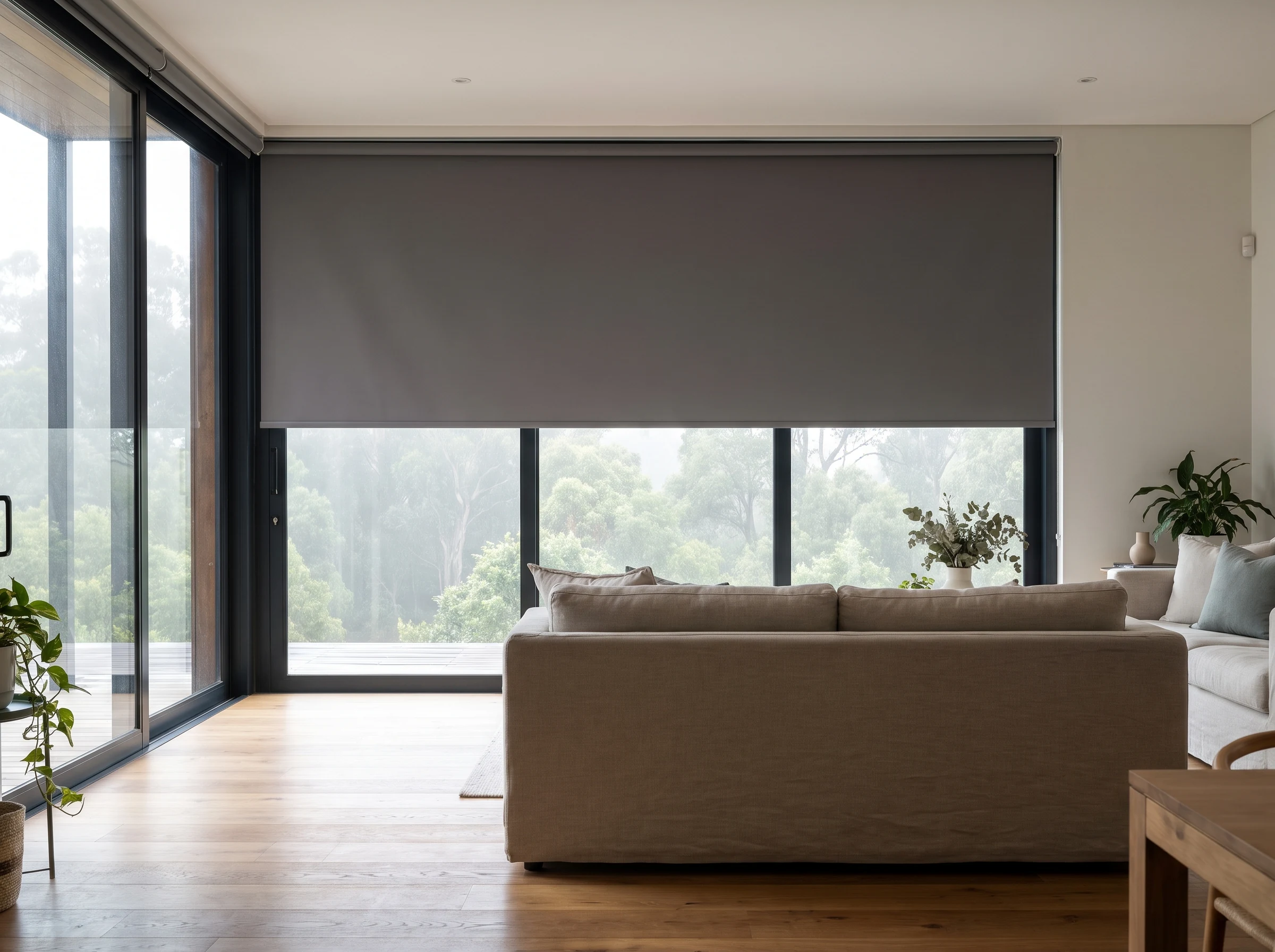 Blockout roller blind half-lowered over a forest-facing lounge window in a George home